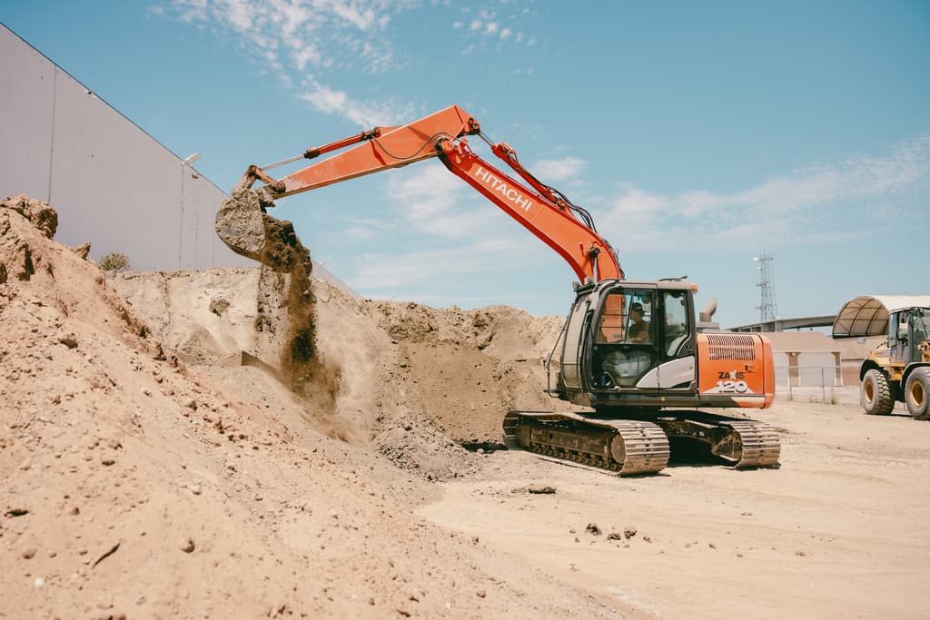 Excavator lifting a full bucket over the stockpile