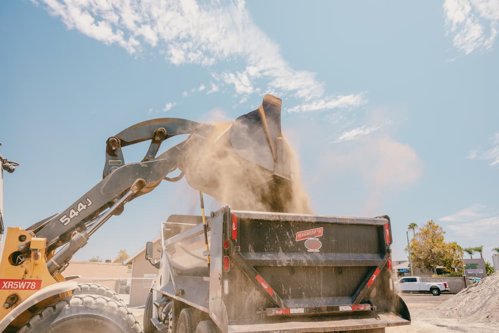 Wheel loader tipping a full bucket of dirt into a dump truck bed