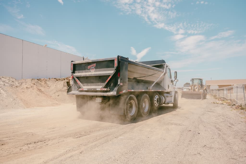 Dump truck rolling through the yard with dust coming off the tires